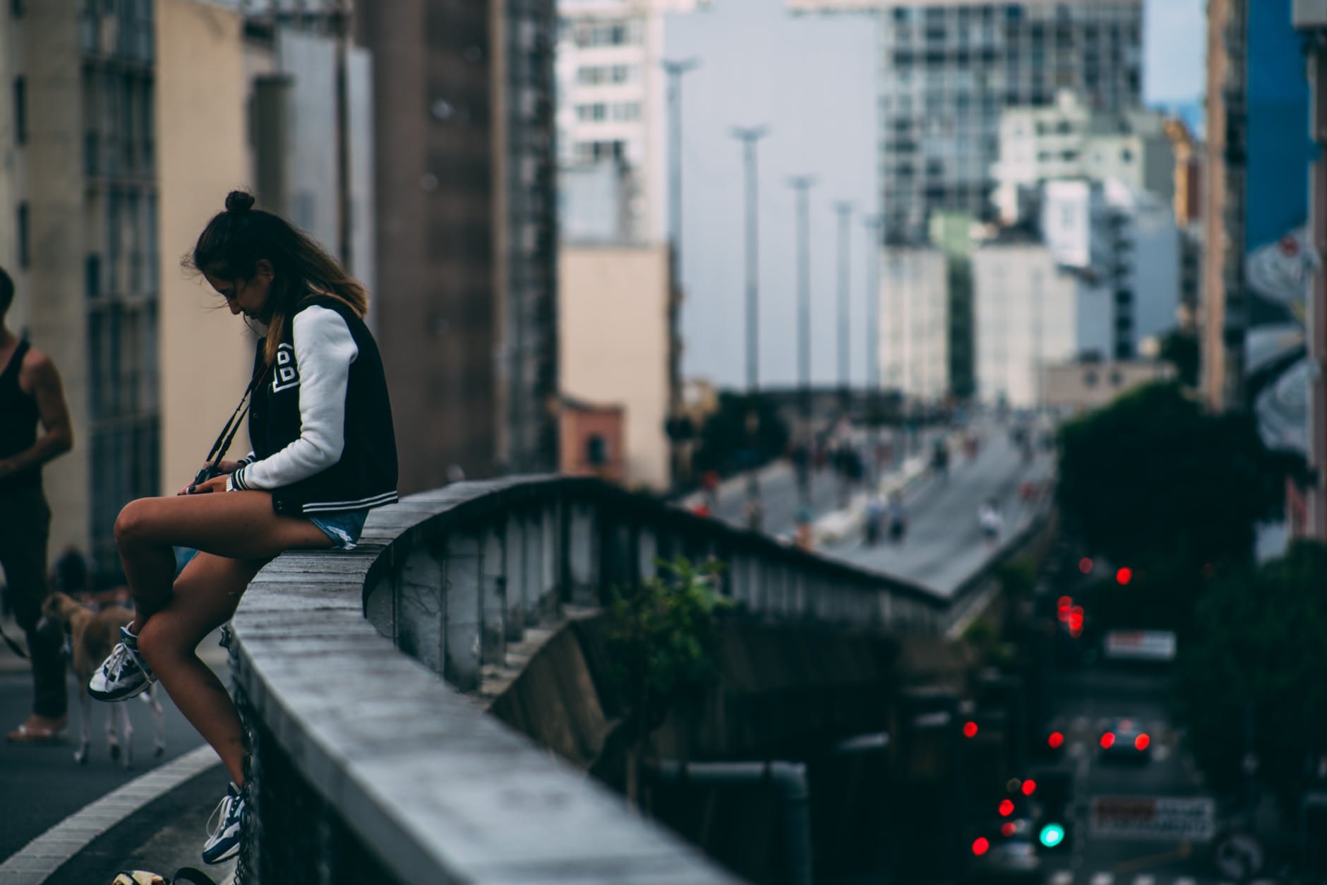 woman sitting on bridge s rail during day