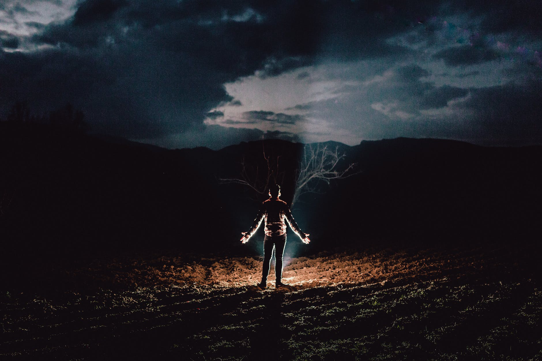 person standing near bonfire with hands to the side