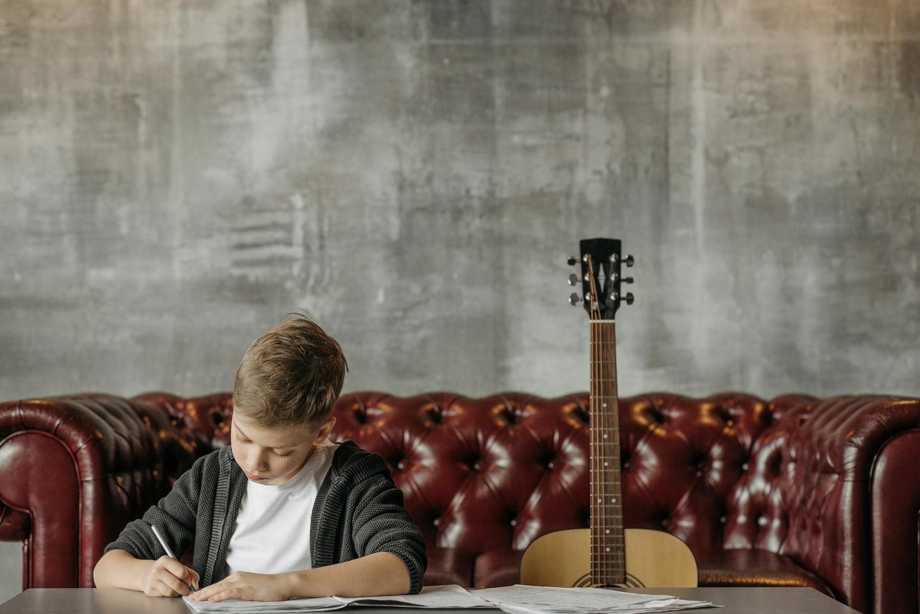 boy writing in a book sitting next to his guitar