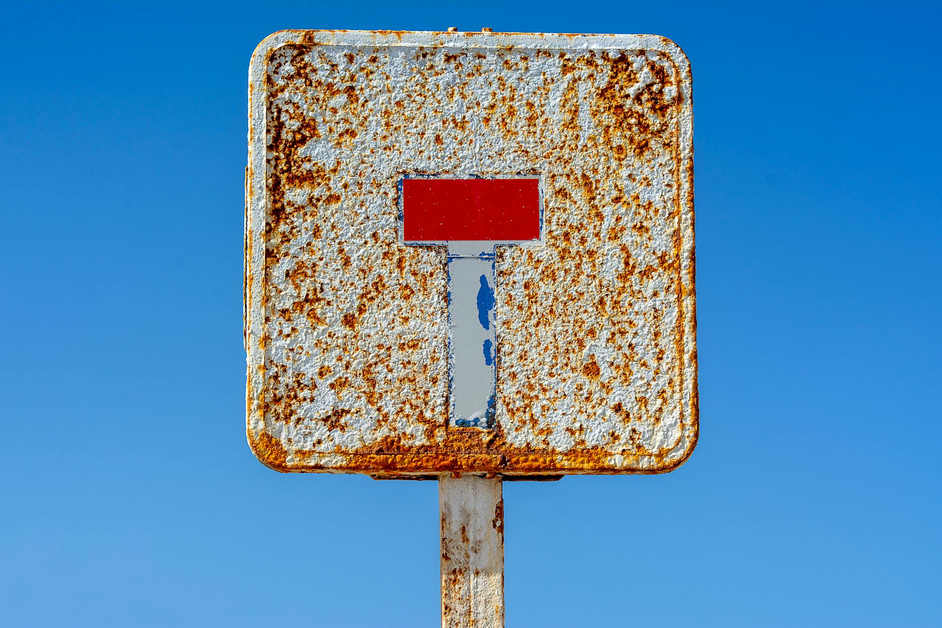 a rusty sign with a red stop sign on it